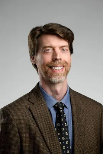 A man in a suit and tie smiling for the camera.